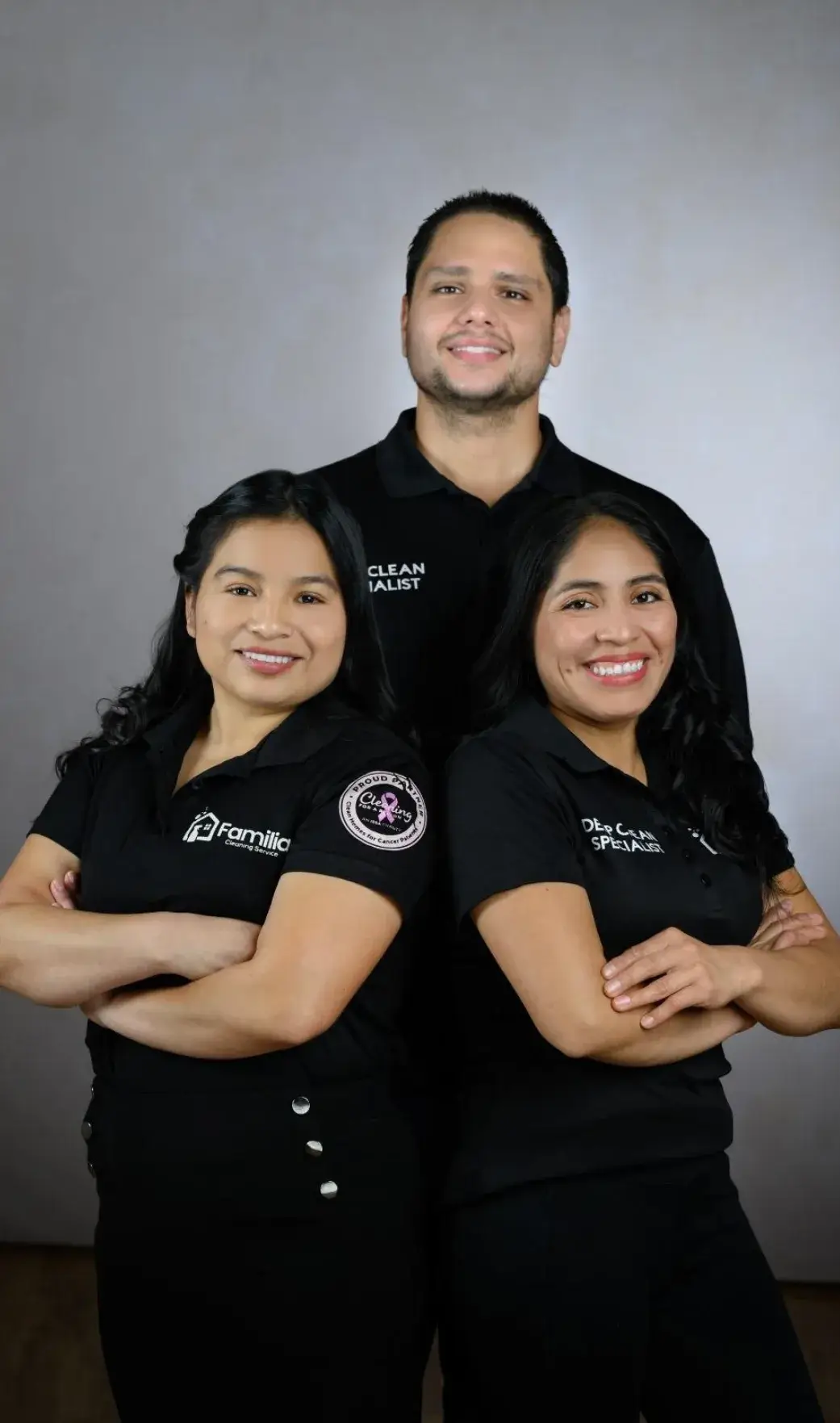 Tres limpiadores profesionales sonrientes de Família Cleaning Services uniformados, que representan servicios de limpieza confiables en Connecticut y Massachusetts.