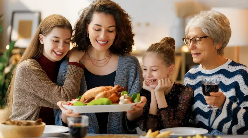 Family gathered around Thanksgiving dinner table smiling and celebrating