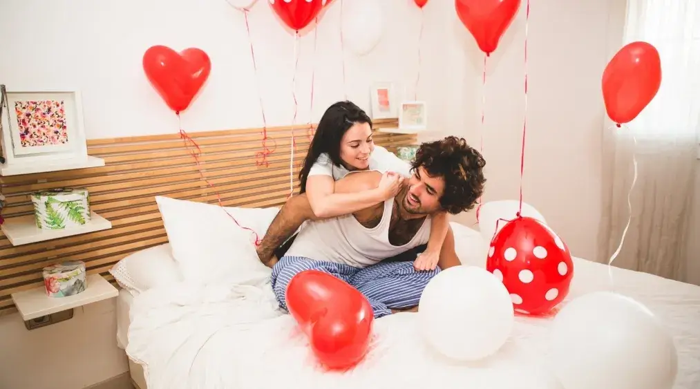 Couple celebrating Valentine’s Day in a clean bedroom with heart balloons